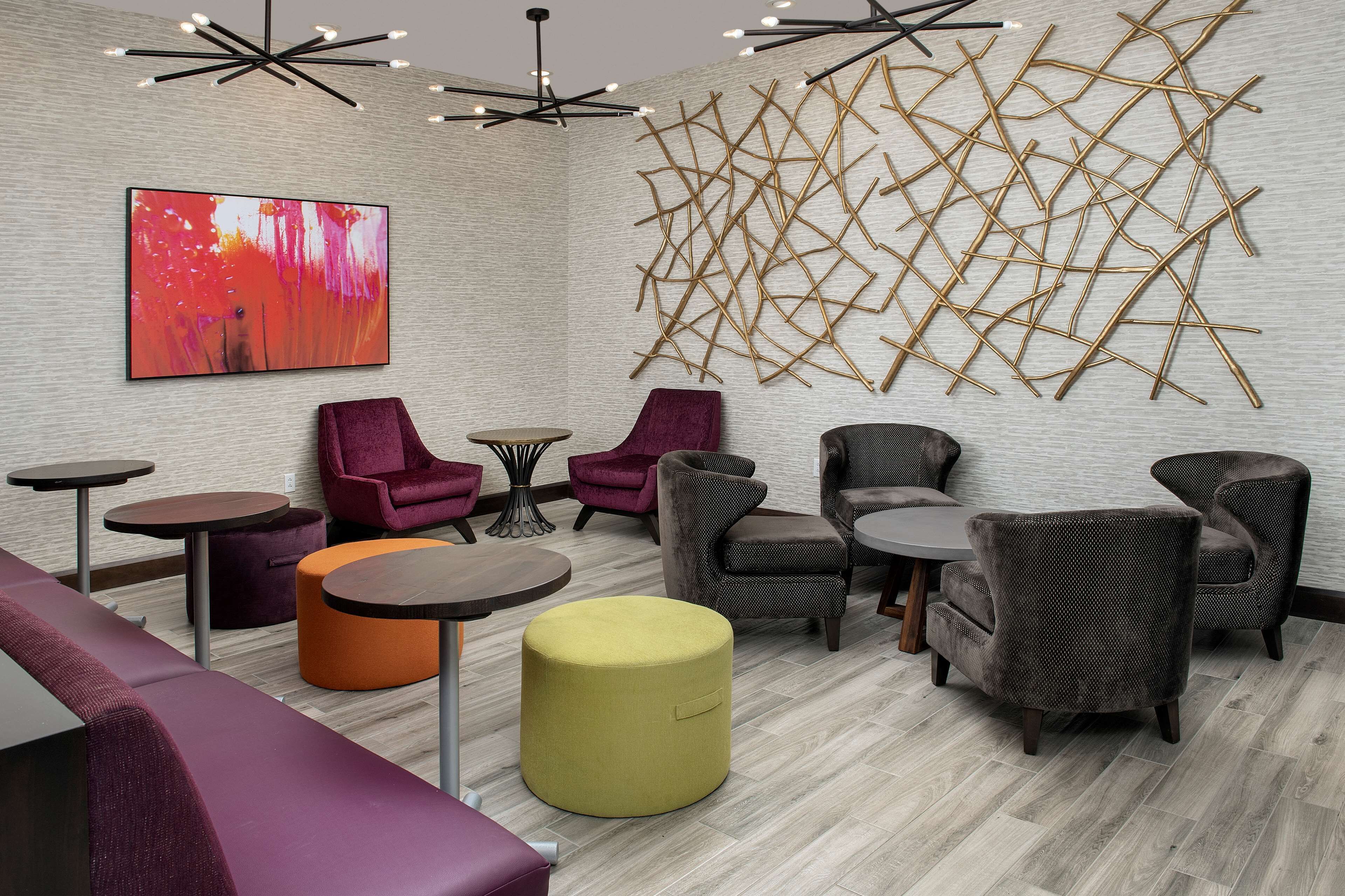 A modern lounge area with seating, tables, and a large abstract painting on the wall.