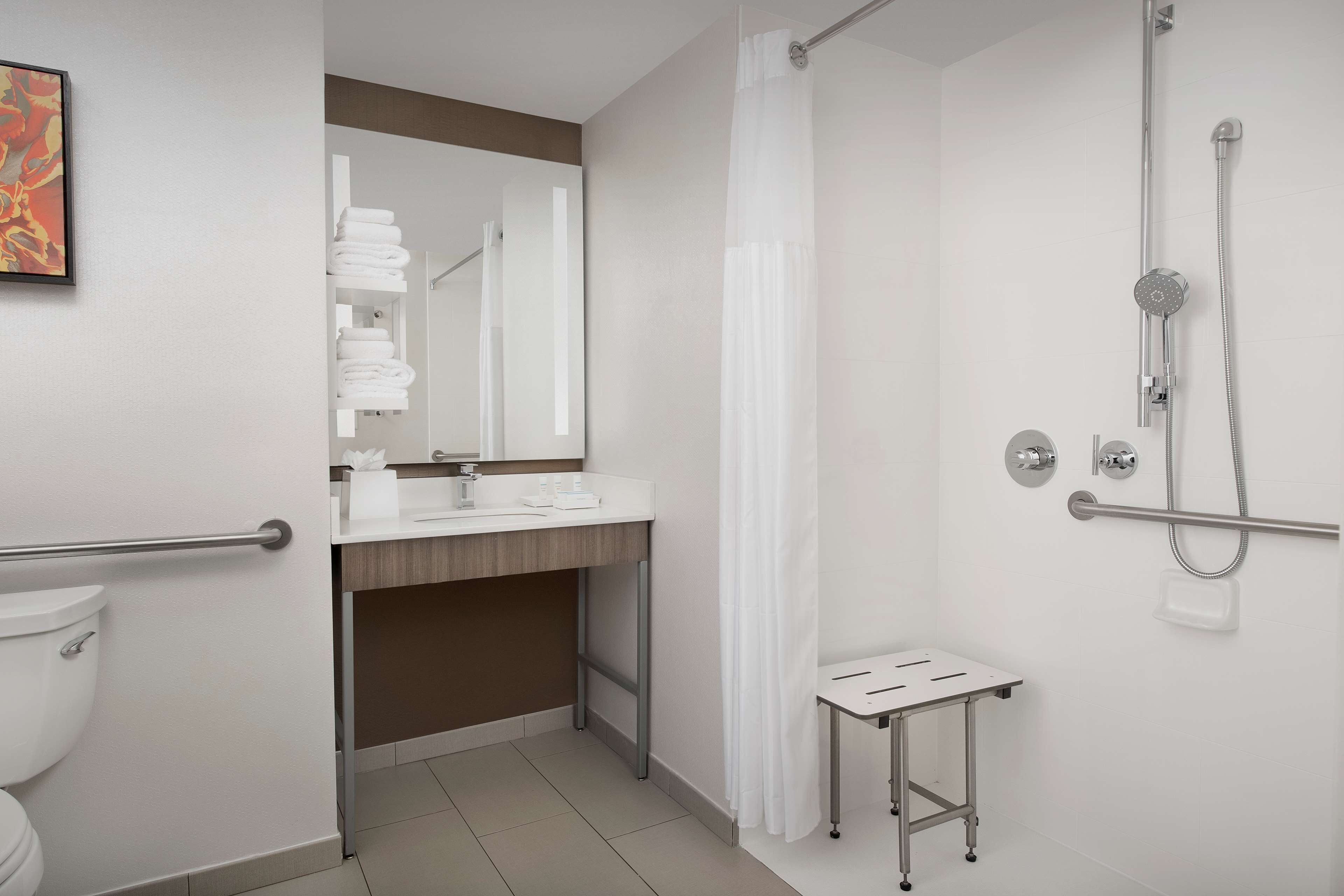 A modern bathroom with a shower, toilet, sink, and a small table.