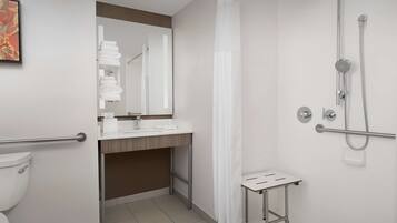 A modern bathroom with a shower, toilet, sink, and a small table.