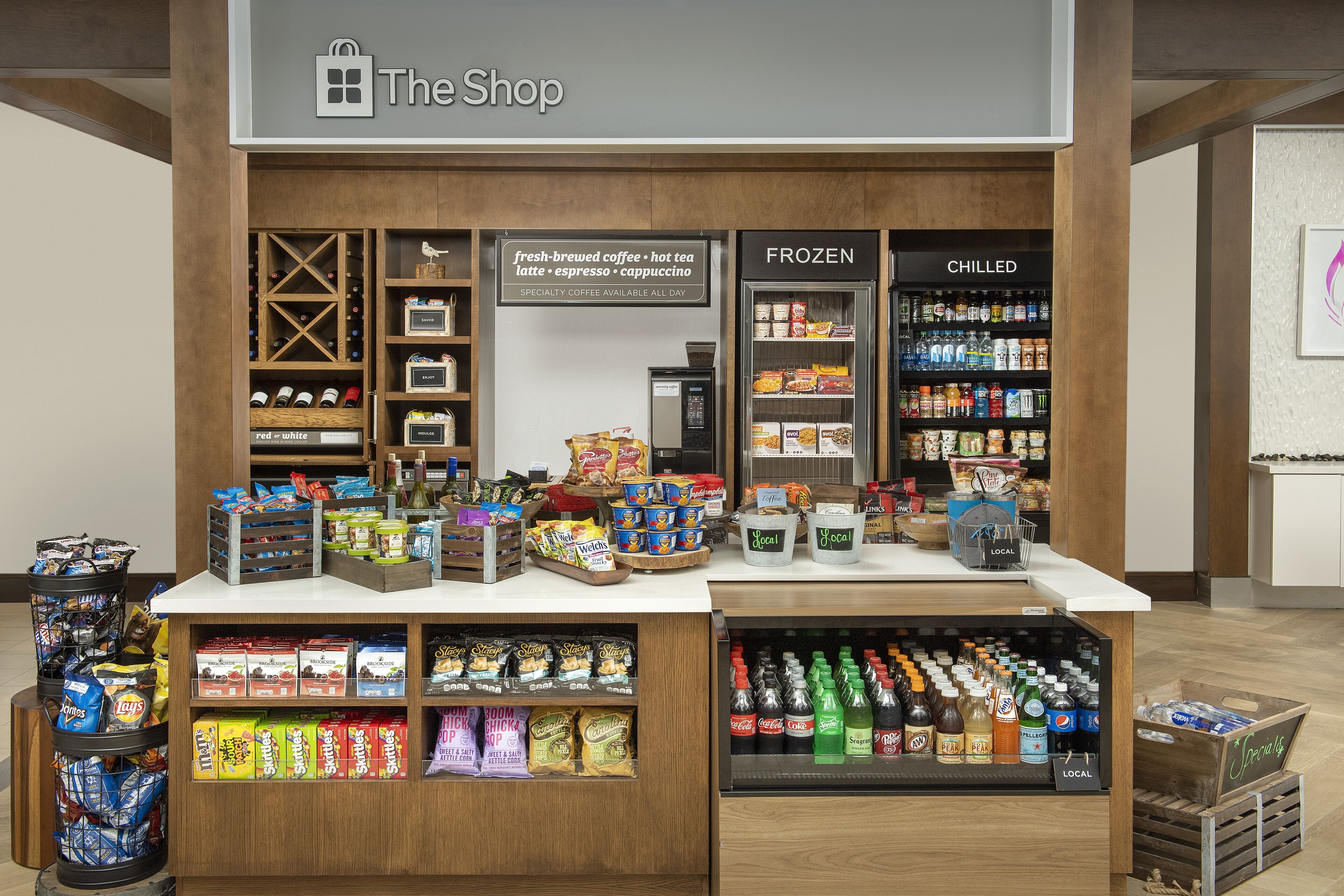 A shop with shelves of snacks, beverages, and a refrigerated section.
