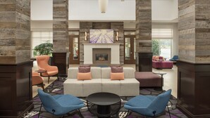 A spacious lobby with a fireplace, comfortable seating, and a large window offering a view.