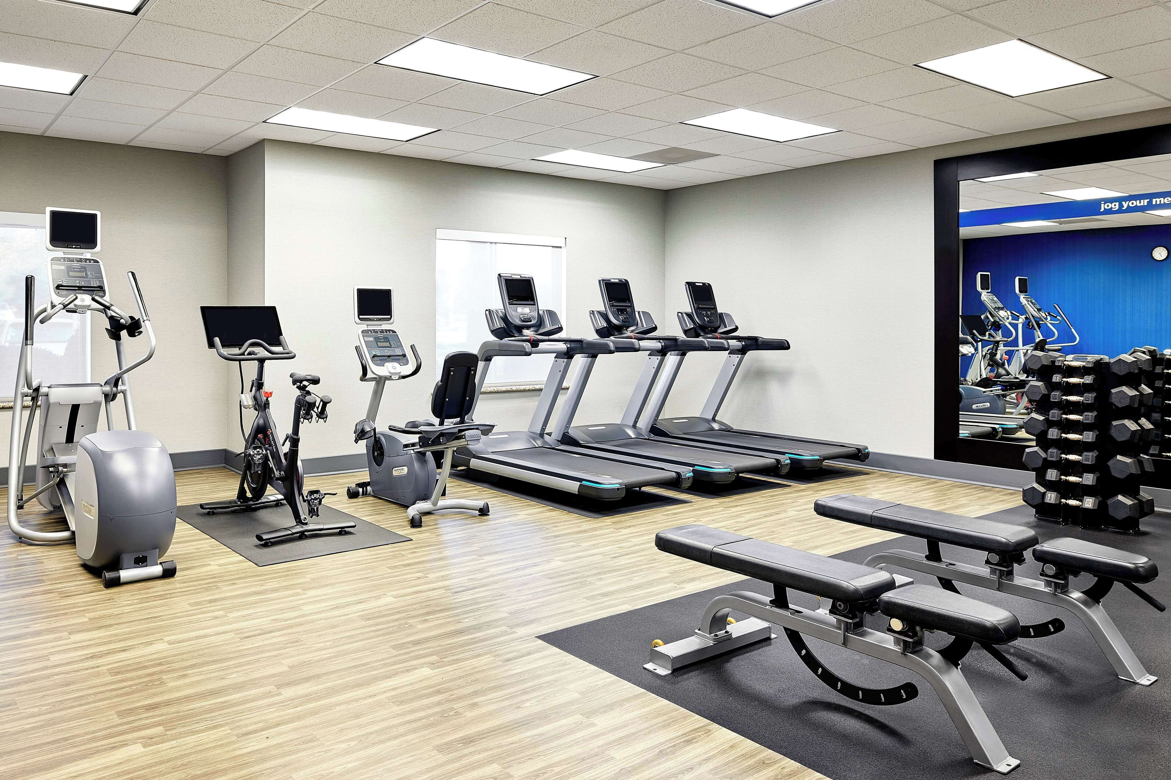 A gym with treadmills, elliptical machines, and weight benches.