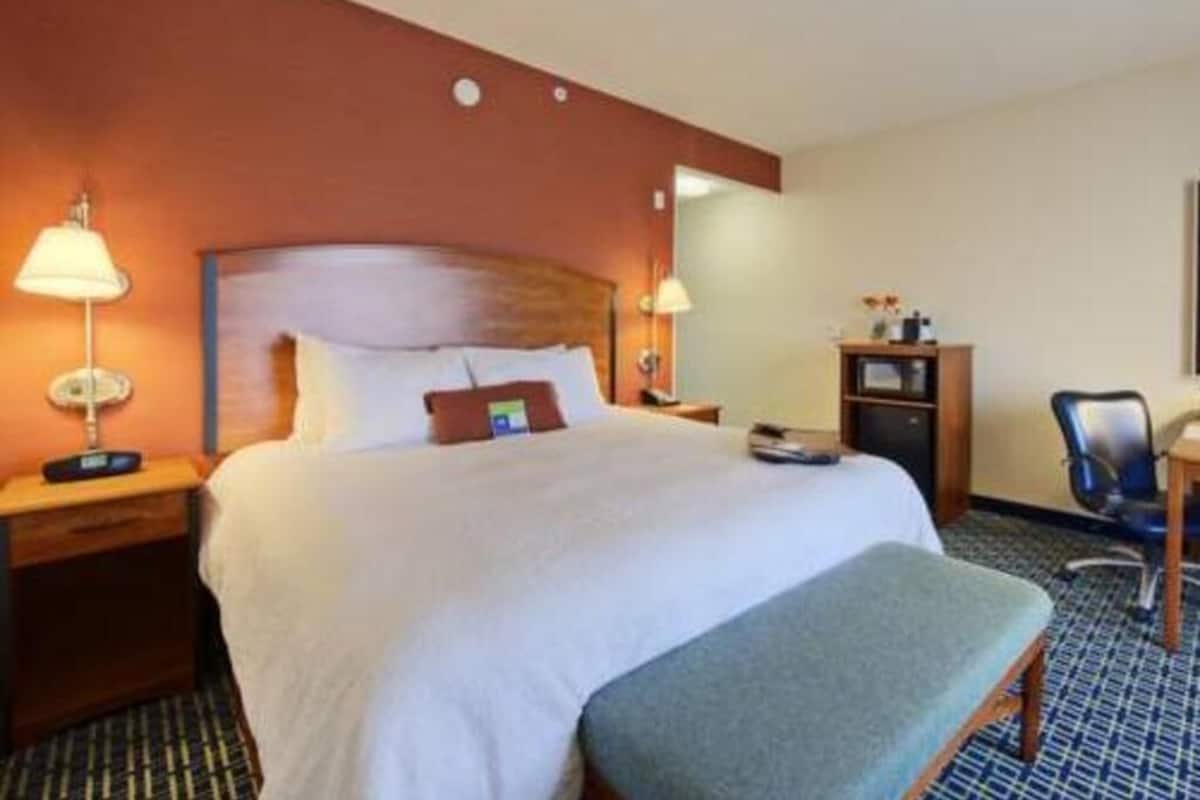 A hotel room with a large bed, bedside tables, a desk, and a chair.