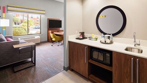 A modern kitchen with a microwave, sink, and a large mirror. There is a dining area with a chair and a table. - Hampton Inn & Suites Ridgecrest (Ridgecrest)