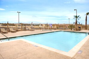 A swimming pool with lounge chairs and a view of mountains in the background.