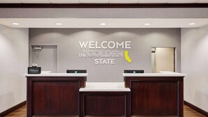 A reception desk with a sign reading "WELCOME THE GOLDEN STATE" and a Hilton Honors logo. - Hampton Inn & Suites Ridgecrest (Ridgecrest)