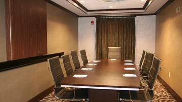 A conference room with a long table, six chairs, and a small podium.