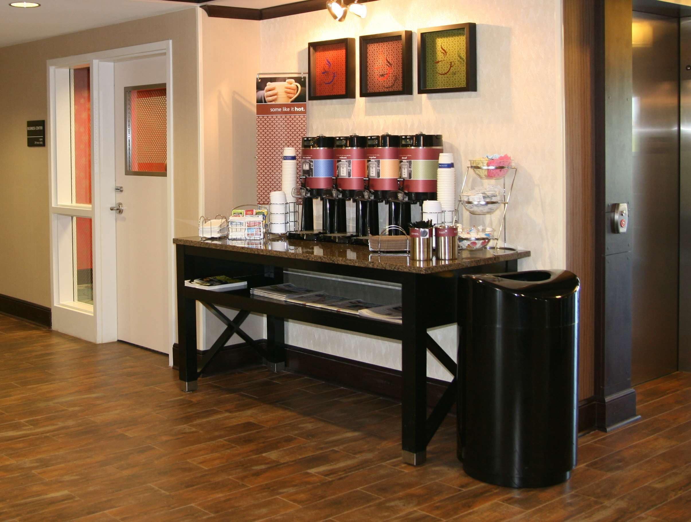 Una estación de café con varias máquinas de café y un cubo de basura.