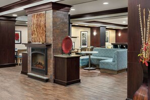 A lobby with a fireplace, seating area, and a decorative wall. - Hampton Inn New Albany (New Albany)