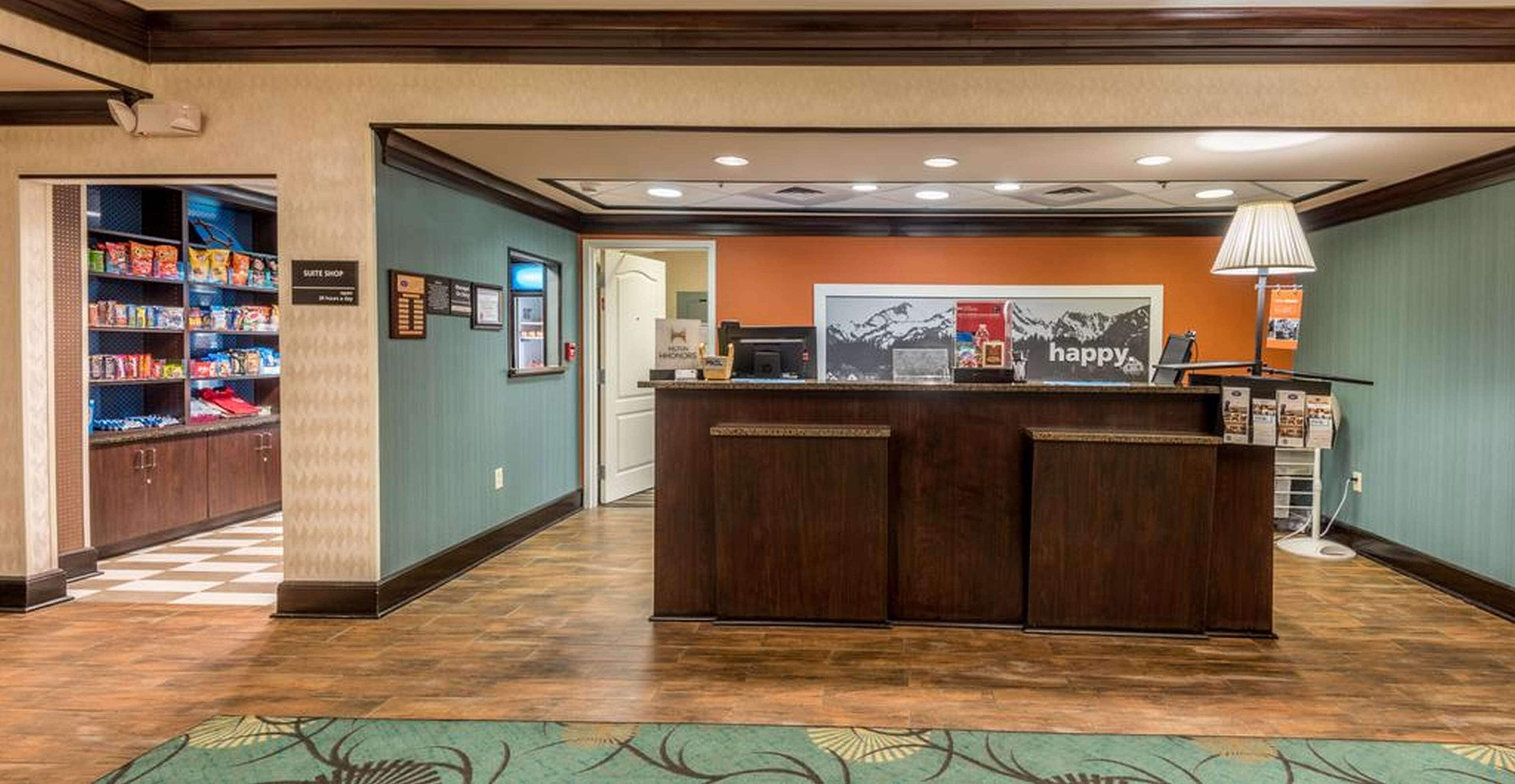 A hotel reception area with a check-in counter, a suite shop, and a display of snacks.