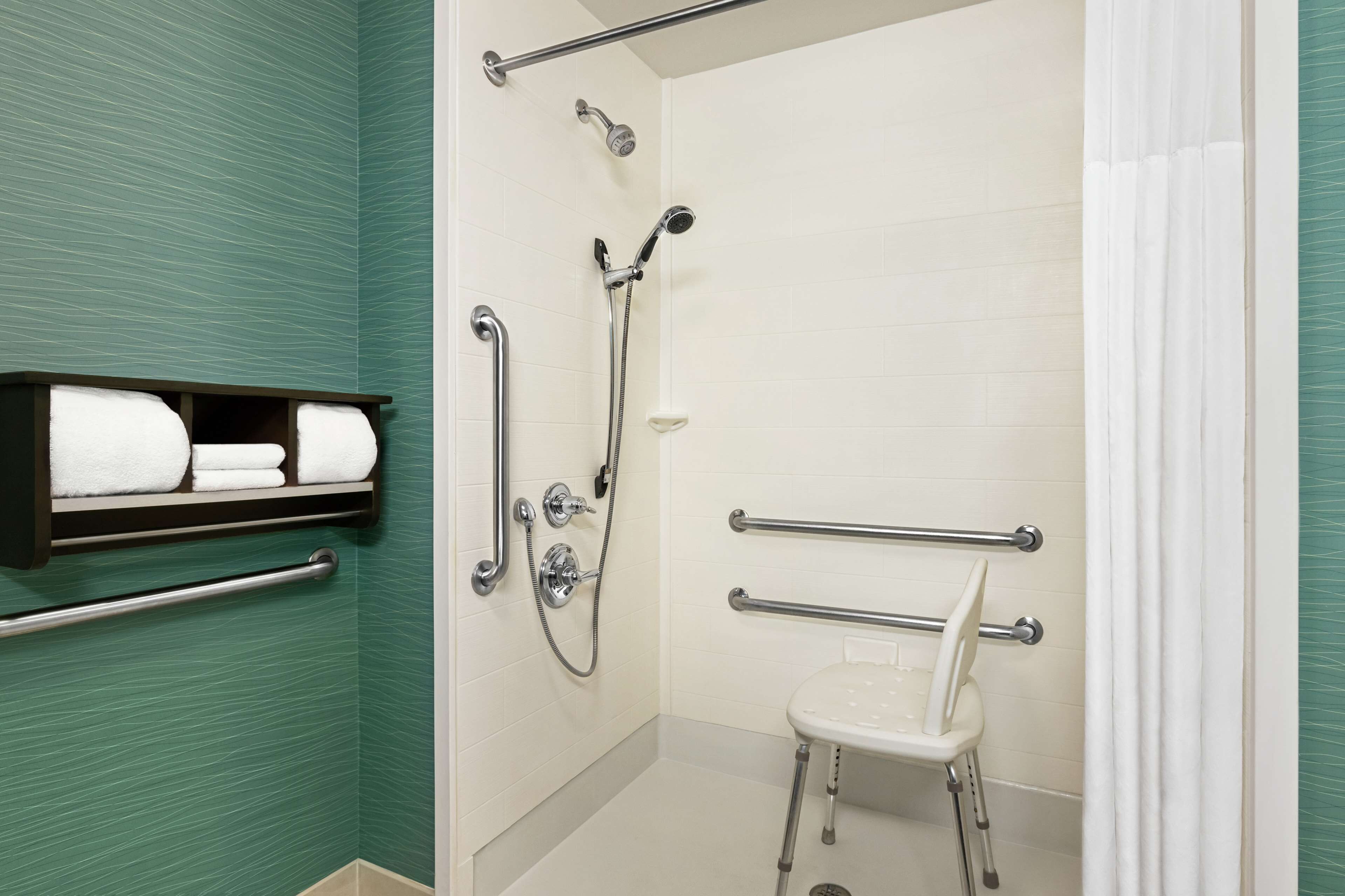 A shower with a handheld showerhead, a handheld showerhead, and a handheld showerhead.
