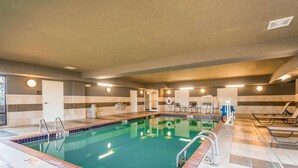 A swimming pool with a tiled deck, a changing room, and a seating area.