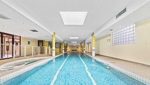 An indoor swimming pool with clear water, tiled walls, and a long, straight layout. - Fiori Apartments (Parramatta)