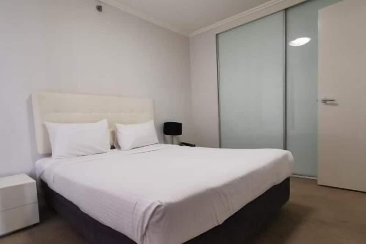 A bedroom with a bed, a nightstand, a lamp, and a sliding door.