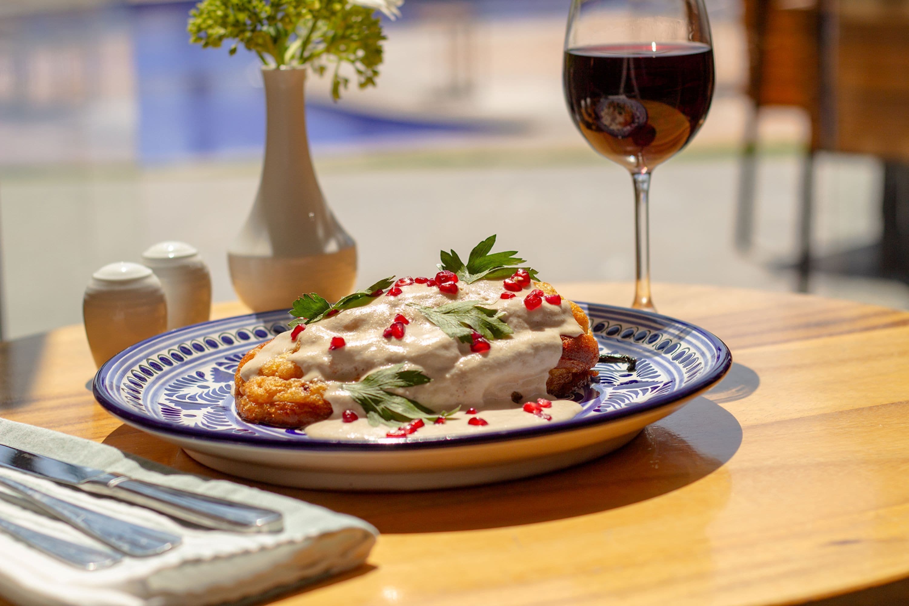 Une assiette de nourriture accompagnée d’un verre de vin rouge, le tout posé sur une table en bois.