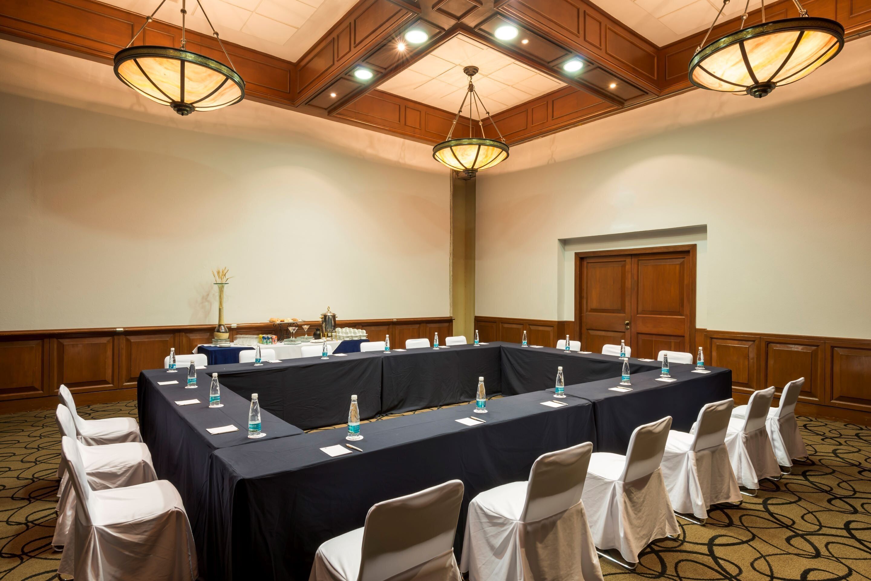 Un salón de conferencias con una larga mesa, sillas y una lámpara de araña.