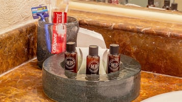Een badkamermeubel met een zeepbakje, drie shampoo flessen en een tandenborstelhouder met een tandenborstel en tandpasta.