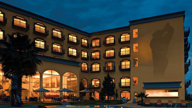 A hotel with multiple balconies, a swimming pool, and outdoor seating areas. - Camino Real Puebla Angelopolis (San Andrés Cholula)
