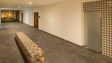 A long hallway with a tiled bench, doors, and a patterned wall.
