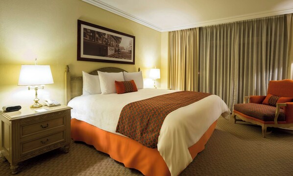 A hotel room with a large bed, two bedside lamps, a nightstand with a phone, a chair, and a framed picture on the wall. - Camino Real Puebla Angelopolis (San Andrés Cholula)