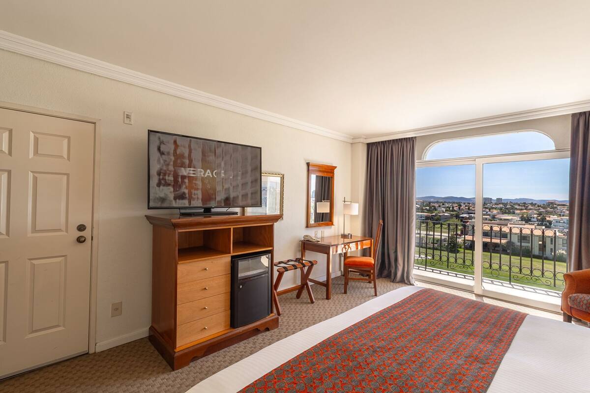 Une chambre d’hôtel avec un grand lit, une télévision, un bureau et une vue sur la ville.