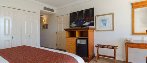 Una habitación de hotel con una cama grande, televisión, escritorio y armario.