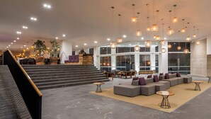 A spacious lobby with a modern design, featuring a seating area with sofas and tables, a staircase, and a reception desk. - Camino Real Puebla Angelopolis (San Andrés Cholula)