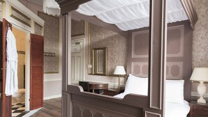 A four-poster bed with a canopy, a wooden desk, a mirror, and a nightstand with a lamp. - Hotel Fidder - Patrick's Whiskybar (Zwolle)