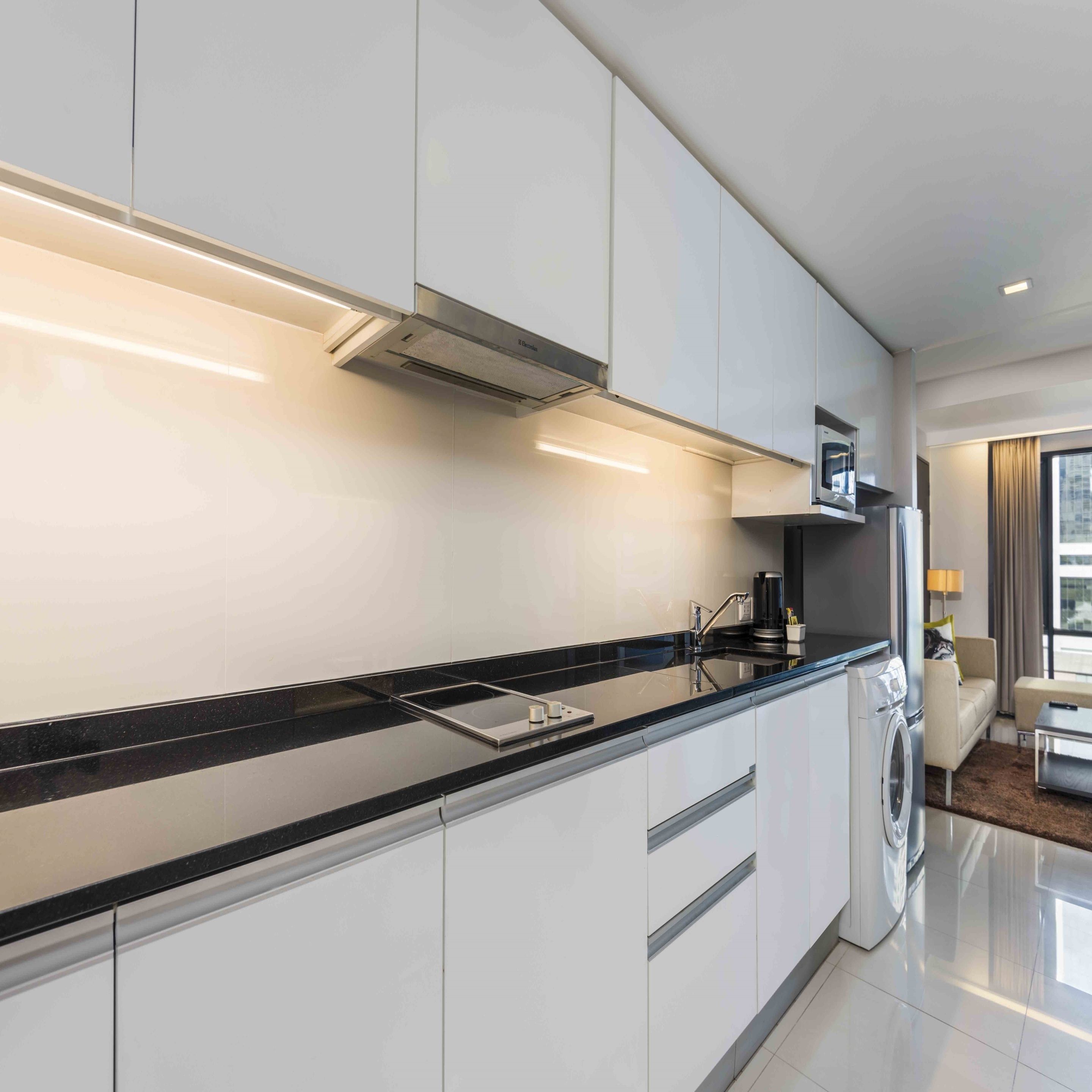 A modern kitchen with white cabinets, a black countertop, and a built-in microwave.