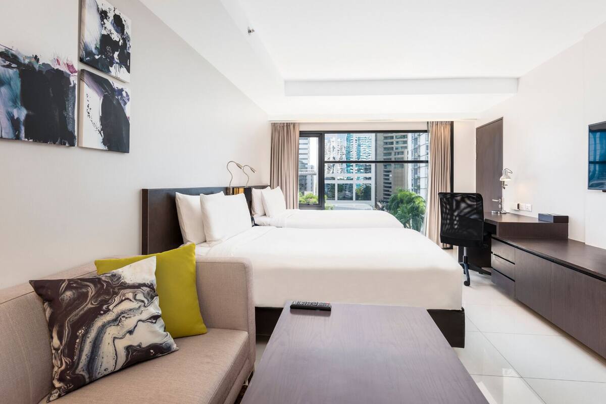 Una habitación de hotel moderna con una cama grande, un sofá, un escritorio y un televisor.