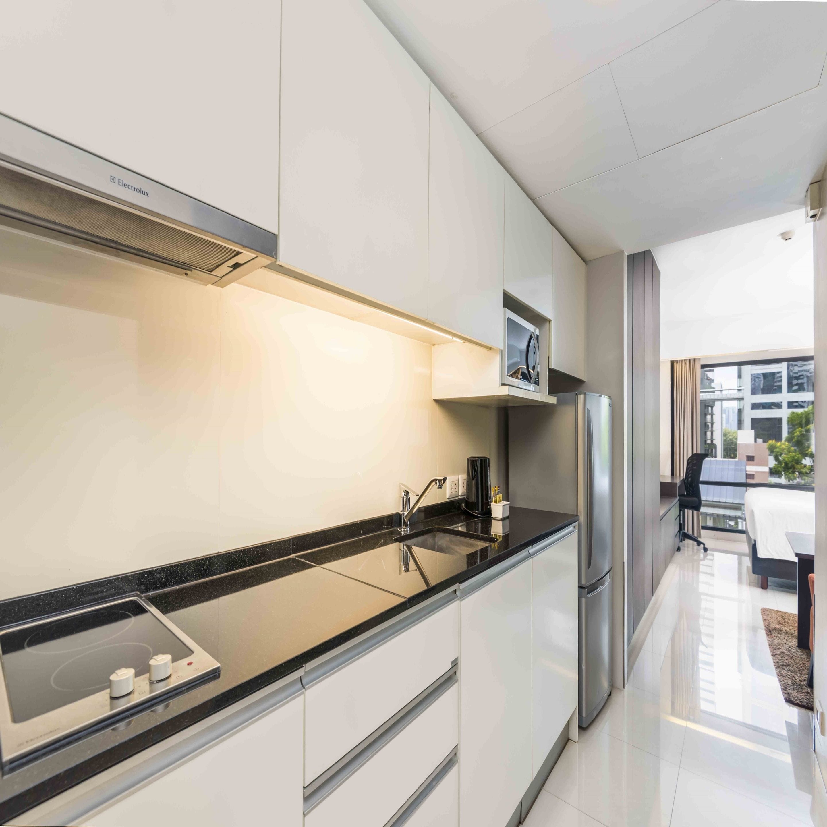 A modern kitchen with white cabinets, a black countertop, and stainless steel appliances.
