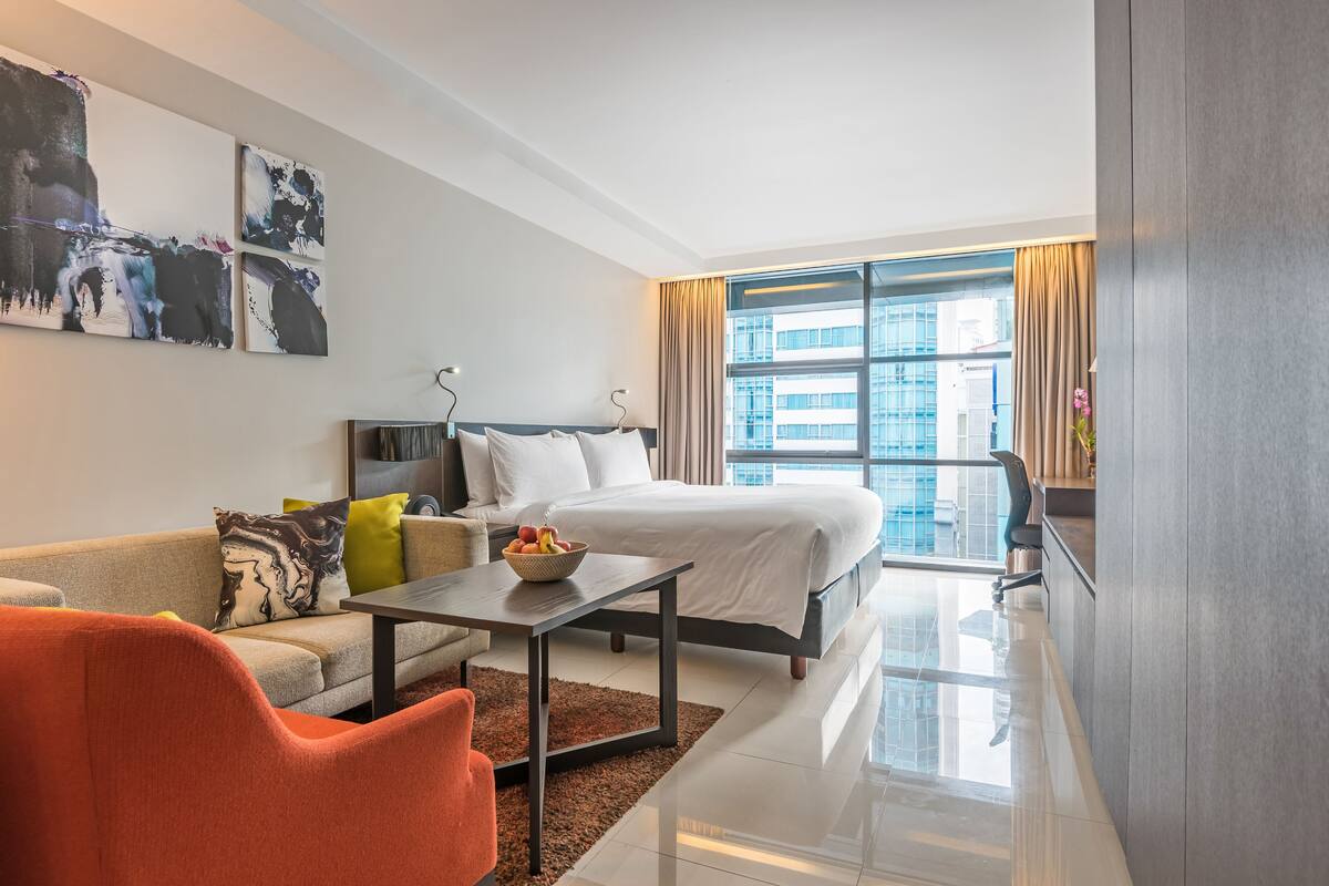 Una habitación de hotel moderna con una cama, un sofá, una mesa de centro y obras de arte en la pared.
