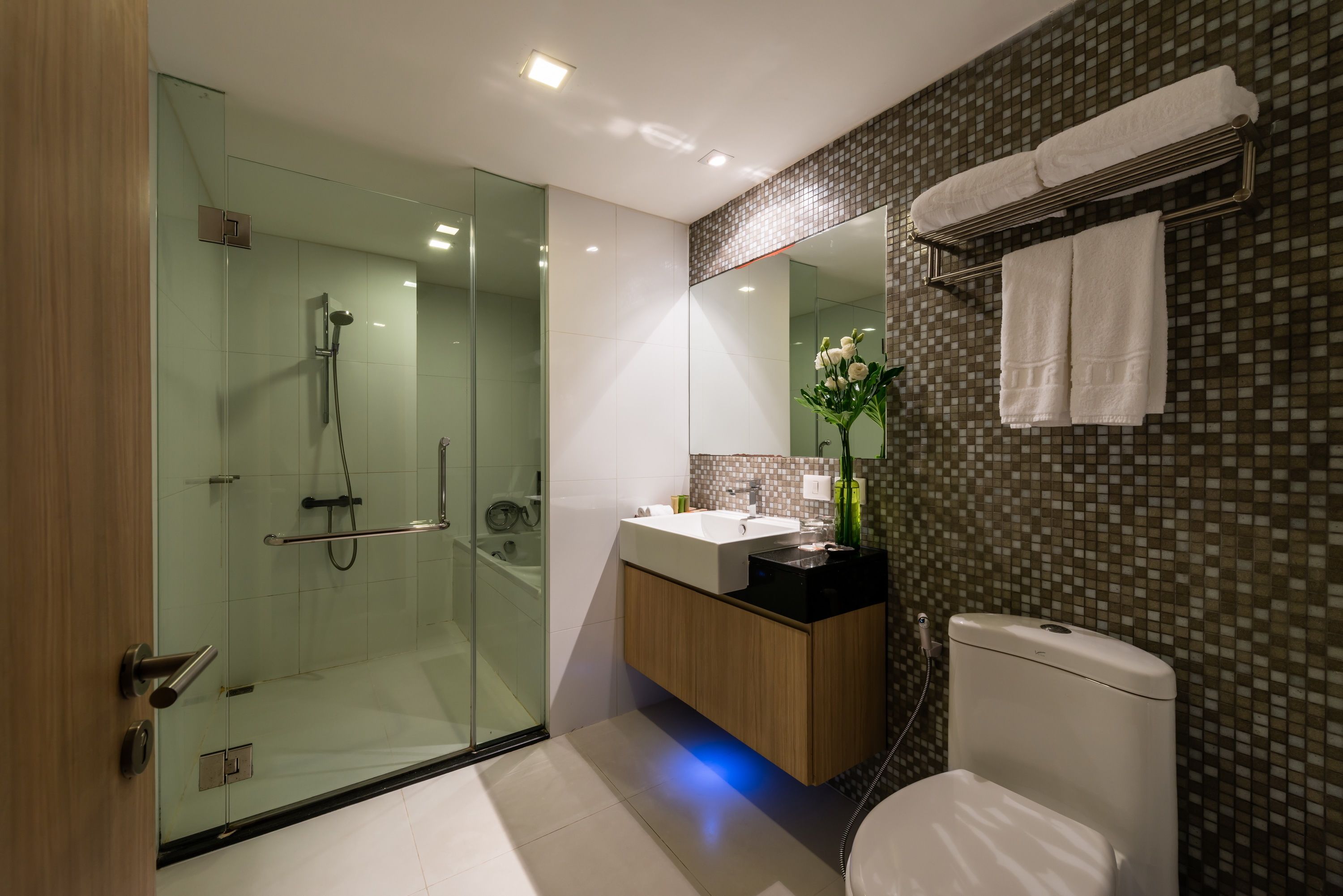 A modern bathroom with a glass-enclosed shower, a wooden vanity with a sink, and a toilet.