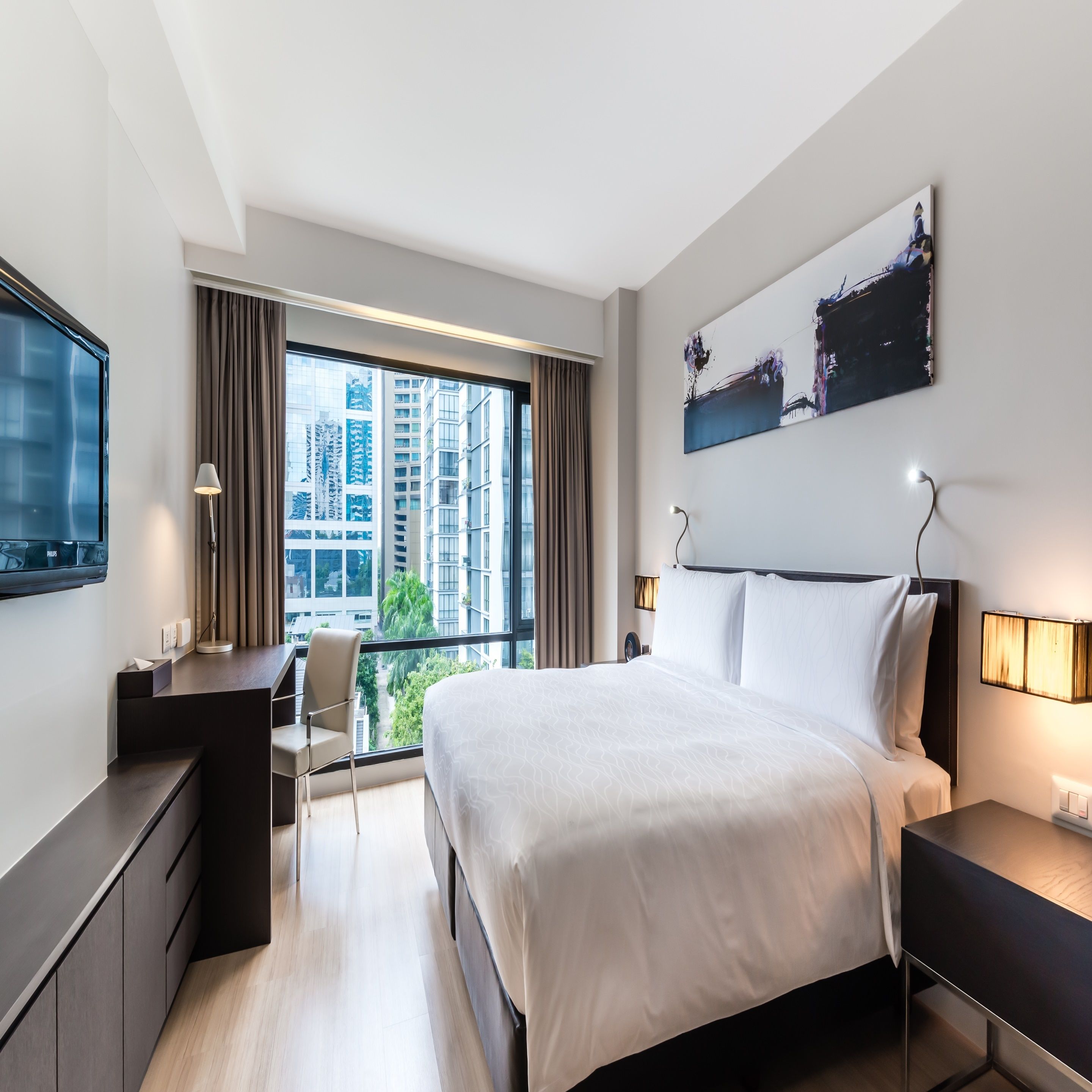 Une chambre d’hôtel moderne équipée d’un grand lit, d’un bureau, d’une chaise et d’une télévision.