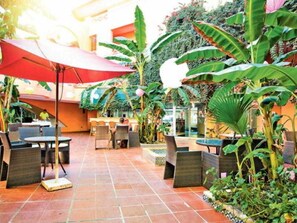 An outdoor patio with tables and chairs, surrounded by lush greenery and plants. - Regency Hammamet (Hammamet)