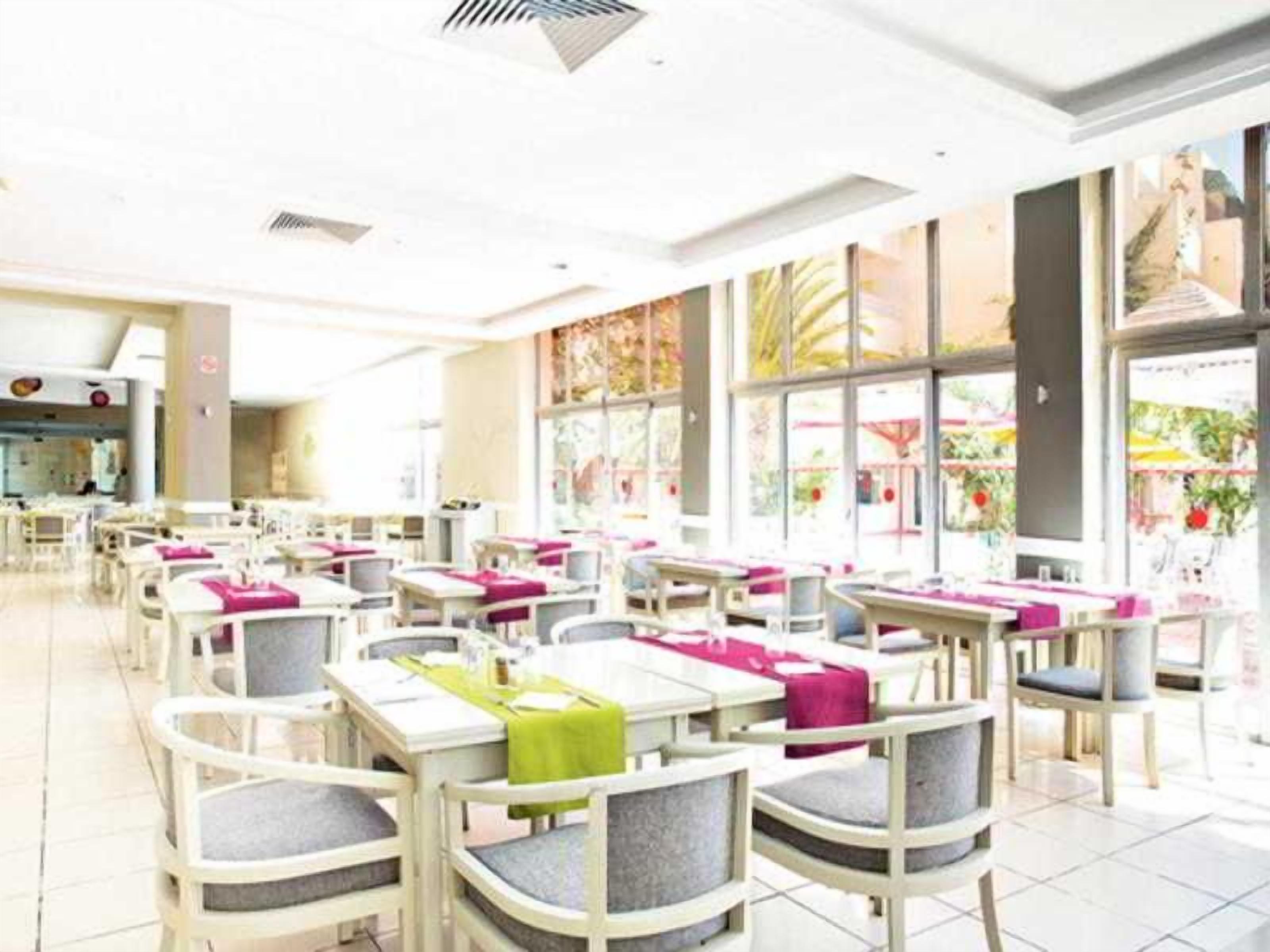 A spacious indoor dining area with multiple tables and chairs, large windows, and a clean, modern design.