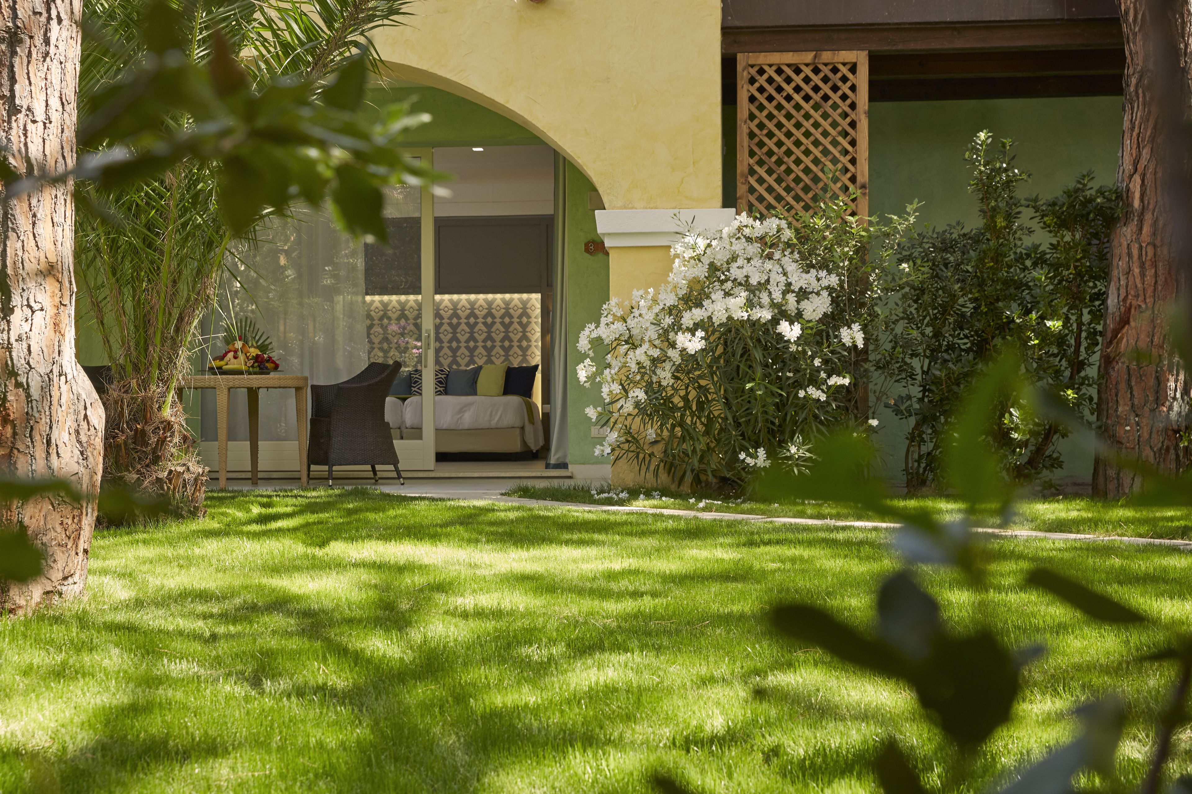 A well-maintained garden with a patio area, a dining table with chairs, and a bed with a patterned bedspread.