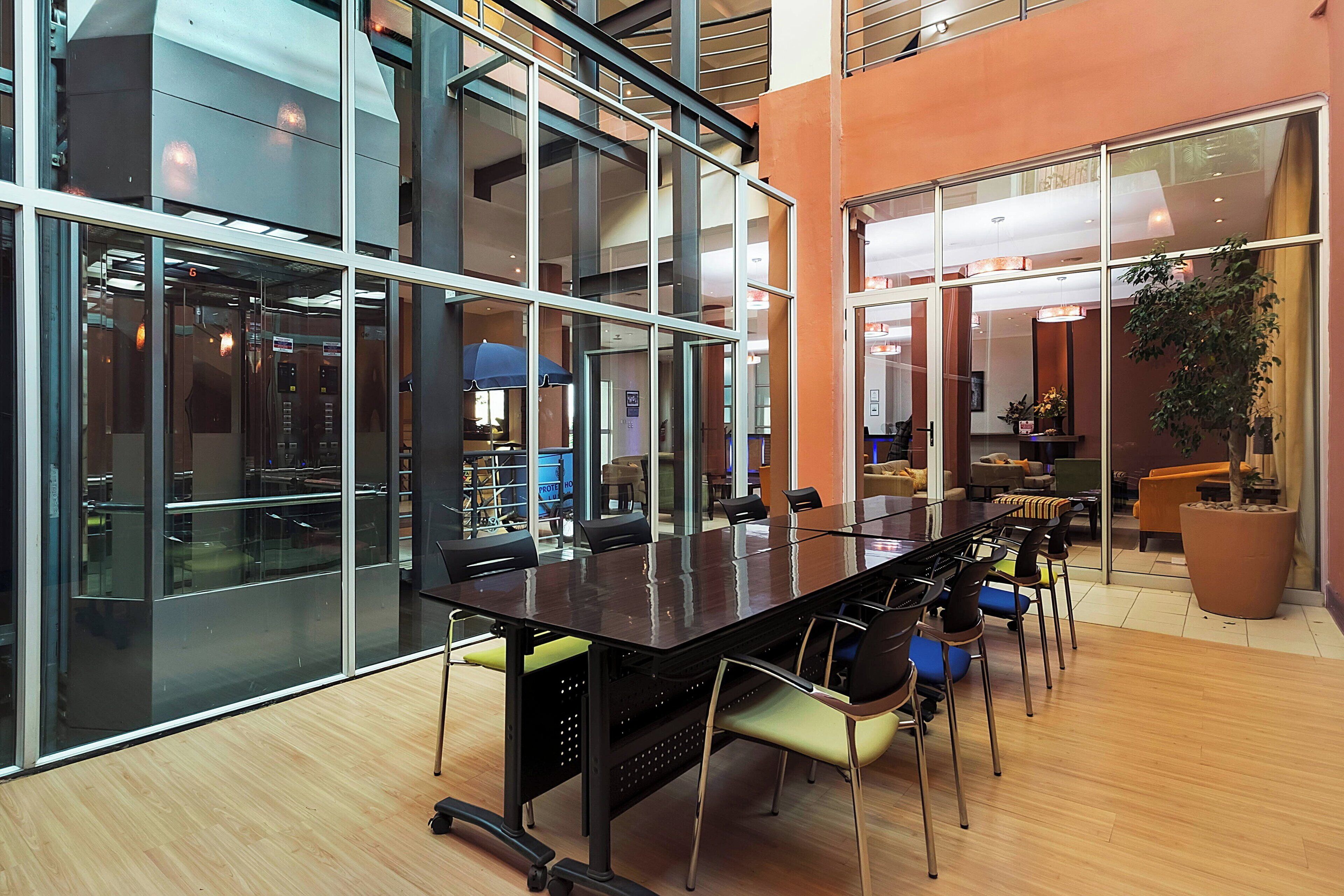 A modern conference room with a long table, chairs, and glass walls.