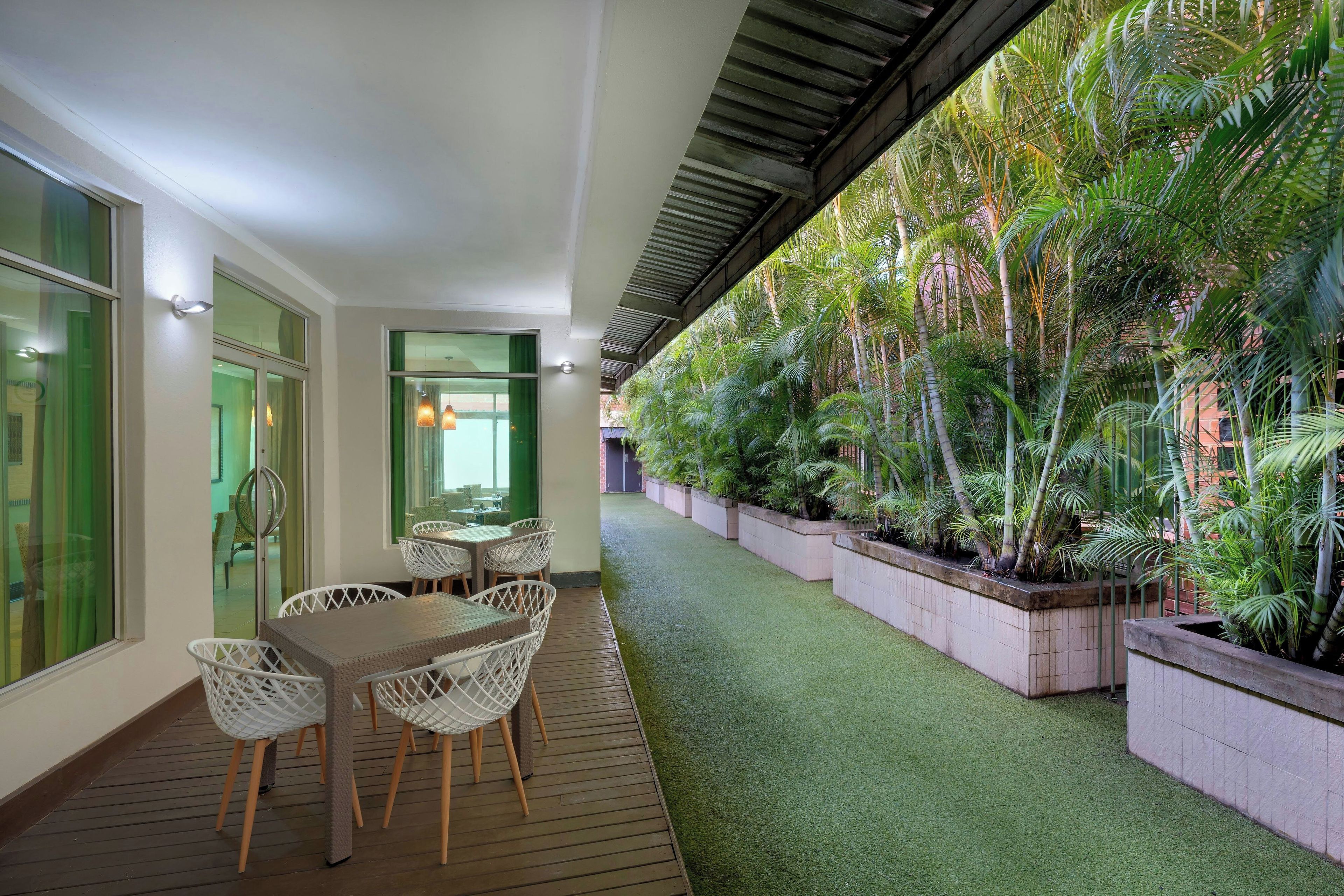 An indoor patio area with a wooden deck, white wicker furniture, and a green artificial turf path.