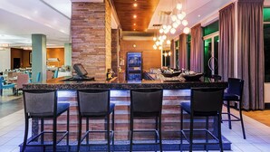 A modern bar area with a wooden ceiling, a stone wall, and a bar counter with seating. - Protea Hotel by Marriott Lusaka (Lusaka)
