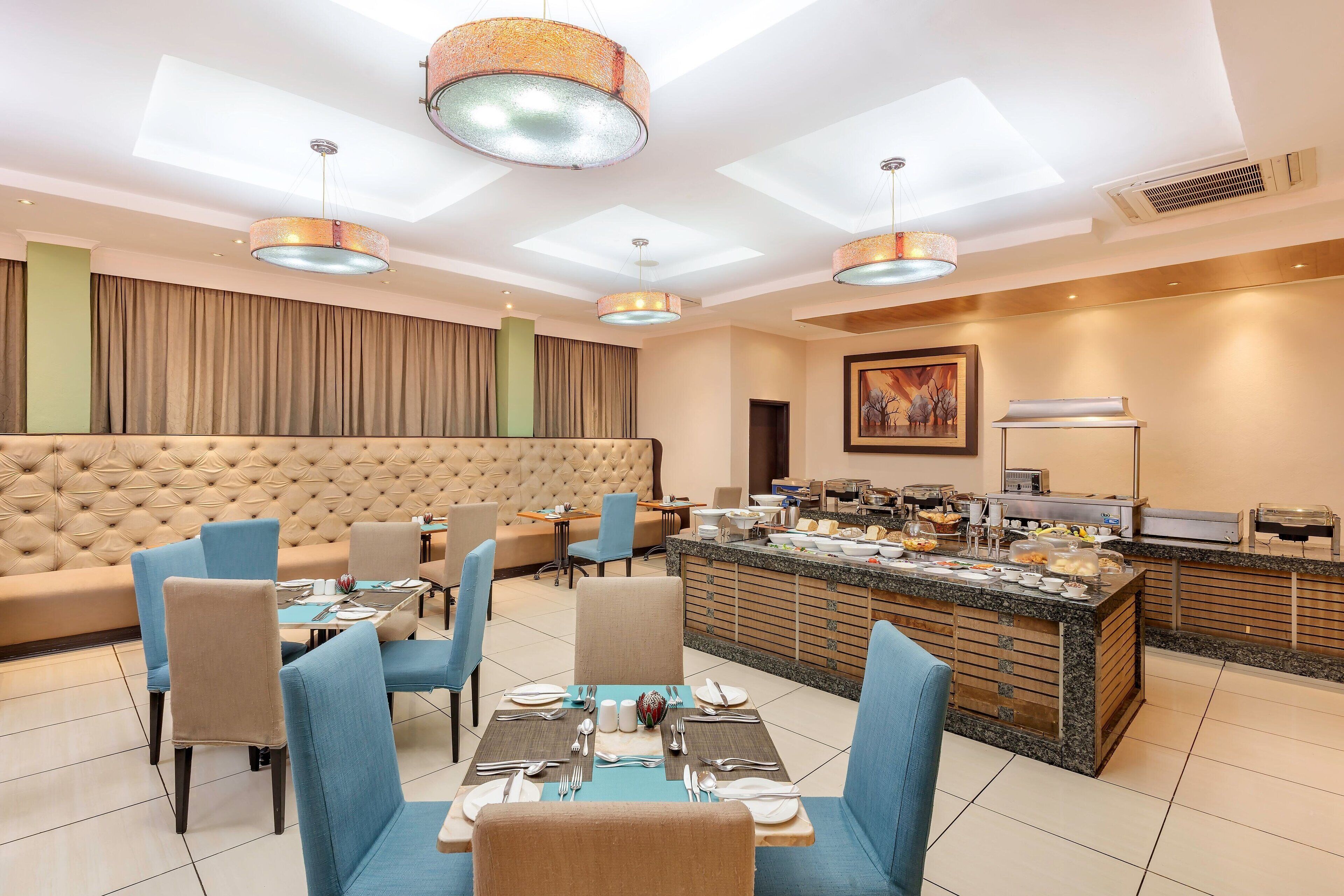 Un comedor de hotel con bufé, asientos acolchados e iluminación moderna.