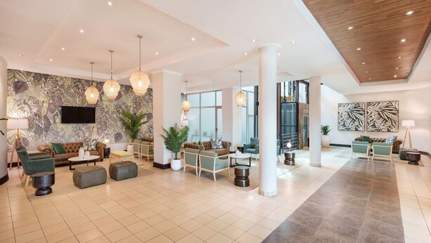 A spacious lobby with a modern design, featuring a mix of seating areas, a large flat-screen TV, and decorative plants. - Protea Hotel by Marriott Lusaka (Lusaka)