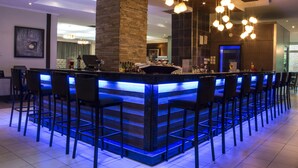 A bar area with a central island, bar stools, and hanging light fixtures. - Protea Hotel by Marriott Lusaka (Lusaka)