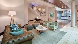 A spacious lobby with a leather sofa, a coffee table, and a staircase leading to an upper level. - Protea Hotel by Marriott Lusaka (Lusaka)