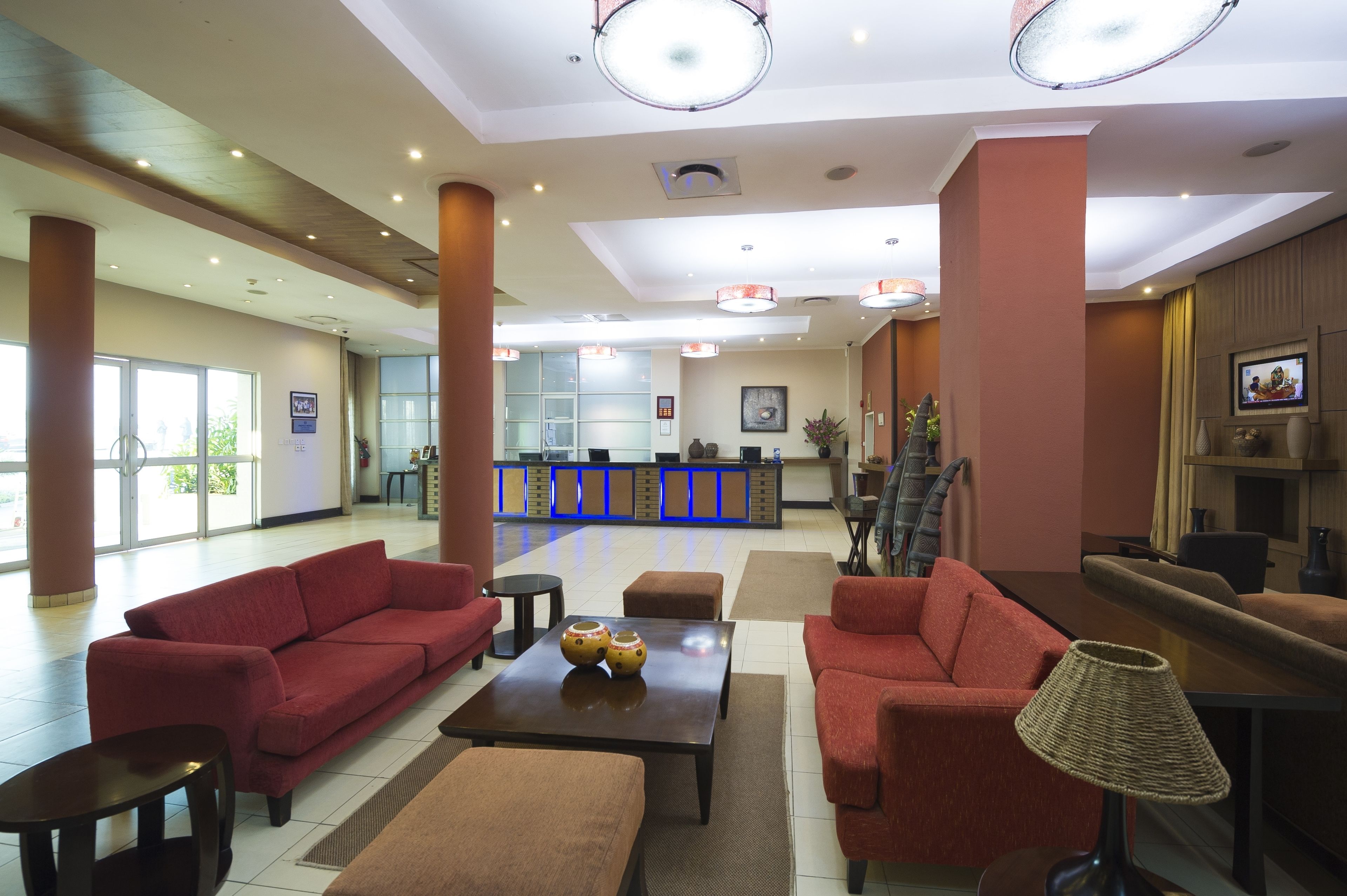 A spacious lobby with red sofas, a reception desk, and a staircase.