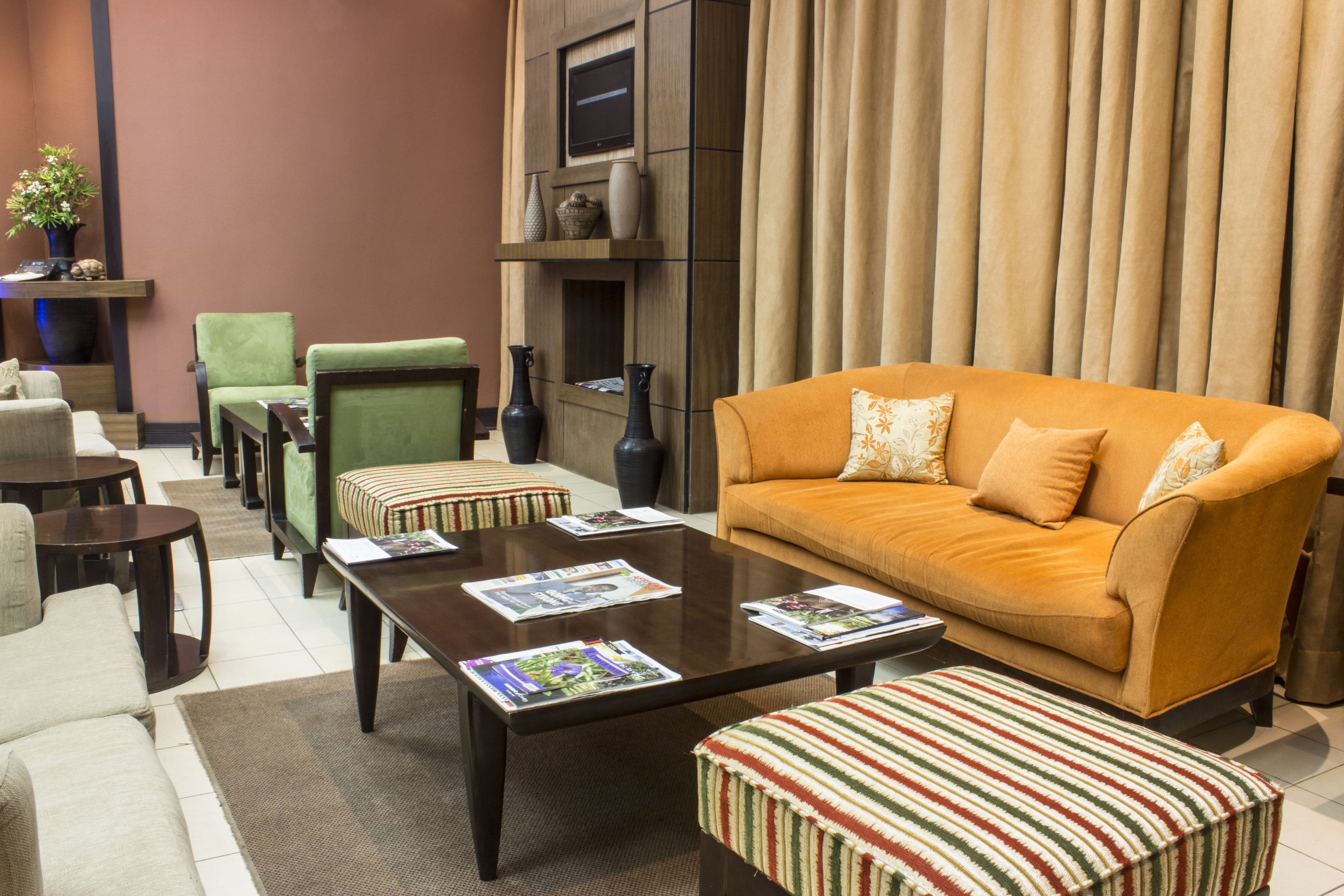 A living room with a sofa, armchairs, a coffee table, and a TV mounted on the wall.