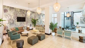 A spacious lobby with a large seating area, a flat-screen TV mounted on the wall, and several hanging pendant lights. - Protea Hotel by Marriott Lusaka (Lusaka)