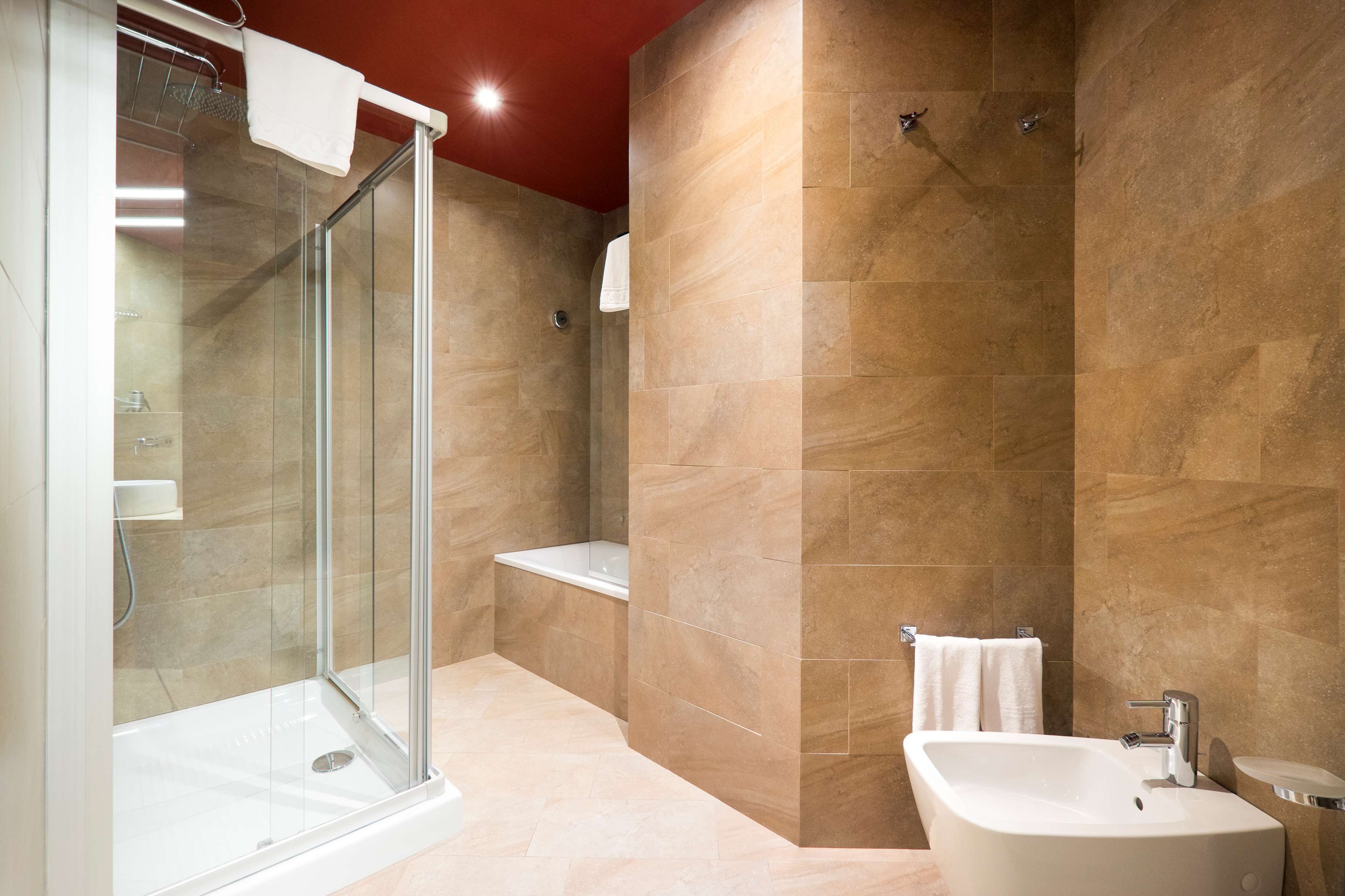 Ein modernes Badezimmer mit einer gläsernen Duschkabine, einer freistehenden Badewanne und einem Waschbecken mit Spiegel.