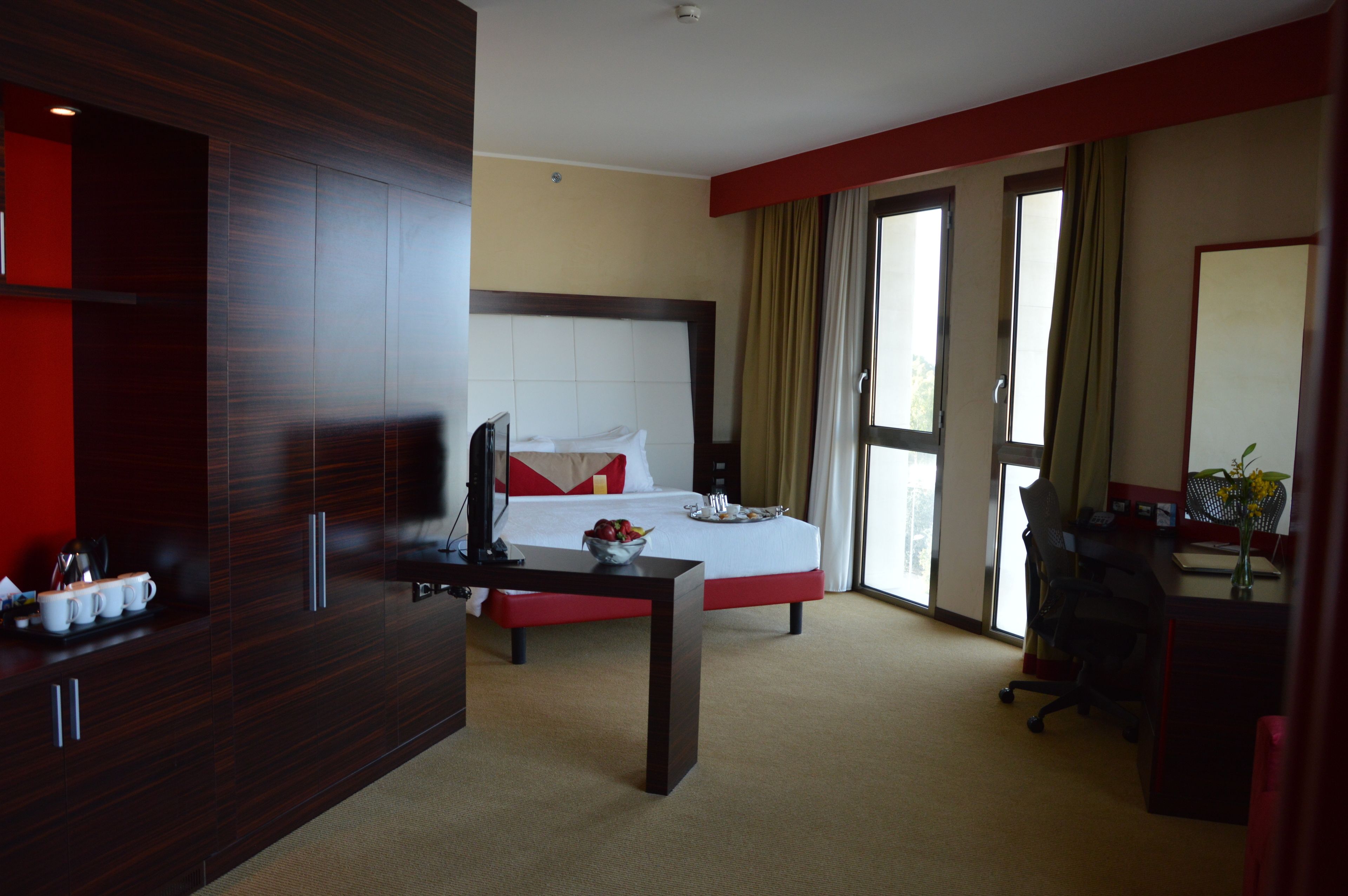 Ein Hotelzimmer mit einem großen Bett, einem Schreibtisch mit Stuhl, einem Fernseher und einem Kleiderschrank.