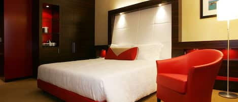 Ein Hotelzimmer mit einem großen Bett, einem roten Sessel und einem roten Kleiderschrank.
